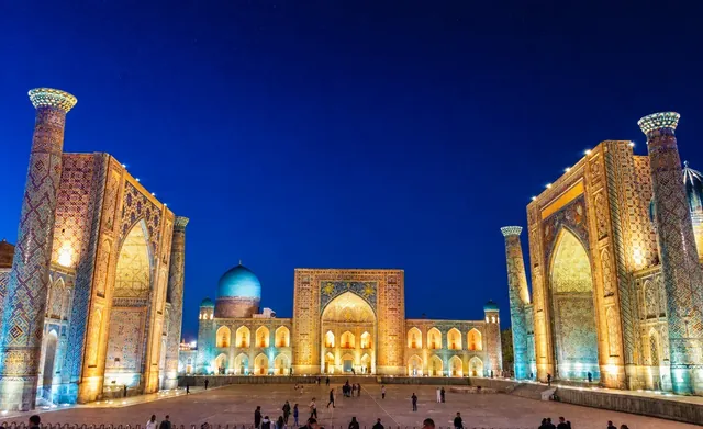 Het verlichte Registan-plein in Samarkand bij avond met indrukwekkende minaretten en koepels